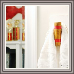 Image (9) Elegant bathroom decor with a plush white towel hanging on a wooden hook, with hints of a stylish vanity and decorative elements in the reflection of the mirror.