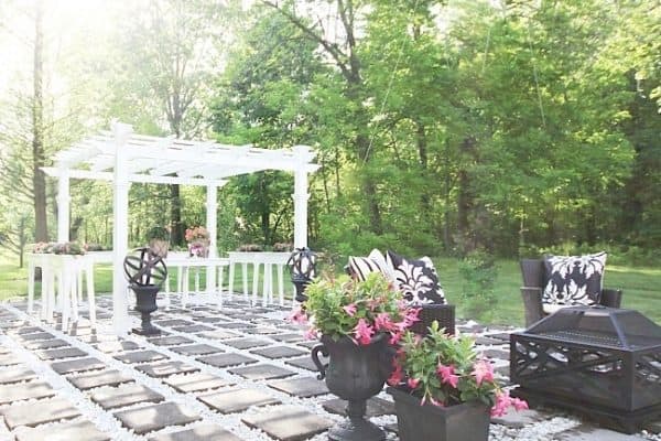 An outdoor garden before and after with a white wooden pergola surrounded by green trees. A stone path leads to the pergola, flanked by potted plants and outdoor benches.