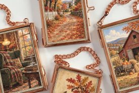 Four hanging wall plaques with copper frames and chains, serving as DIY Christmas decor, each displaying autumn-themed paintings of a cozy room, tree-lined path, barn in a field, and pumpkins.