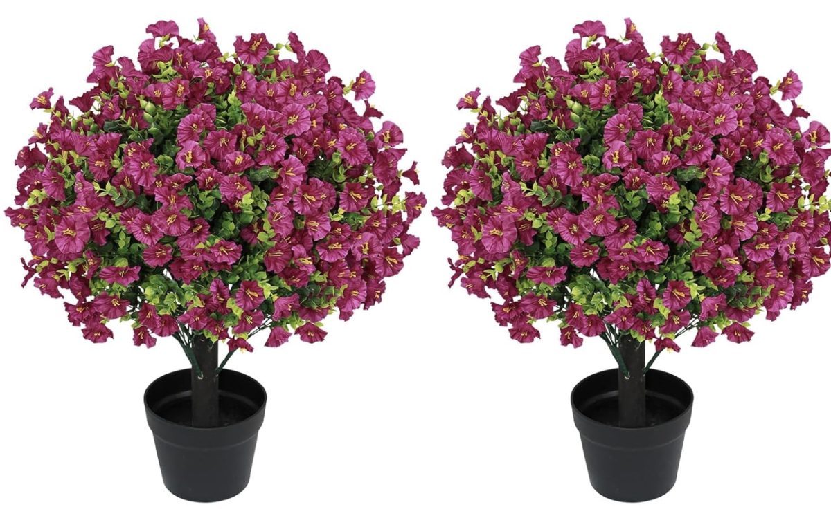 Two identical potted artificial plants with round, bushy clusters of vibrant purple flowers and green leaves, both in black pots, set against a white background.