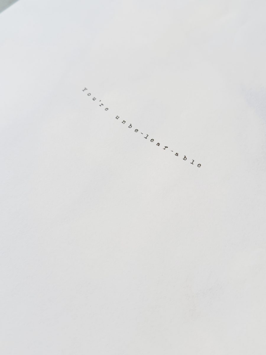 A white sheet of paper with the typed text “You’re unbe-leaf-able” centered in small, spaced-out letters.